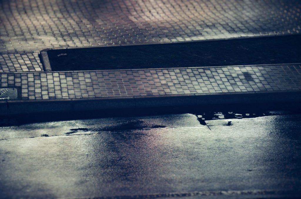 pexels photo 12006840 Moody evening scene of a wet city sidewalk reflecting soft light, captured at twilight.